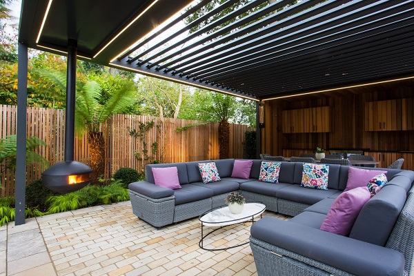 Furniture under louvred pergola on patio of tumbled mint sandstone setts. Design by Barnes Walker