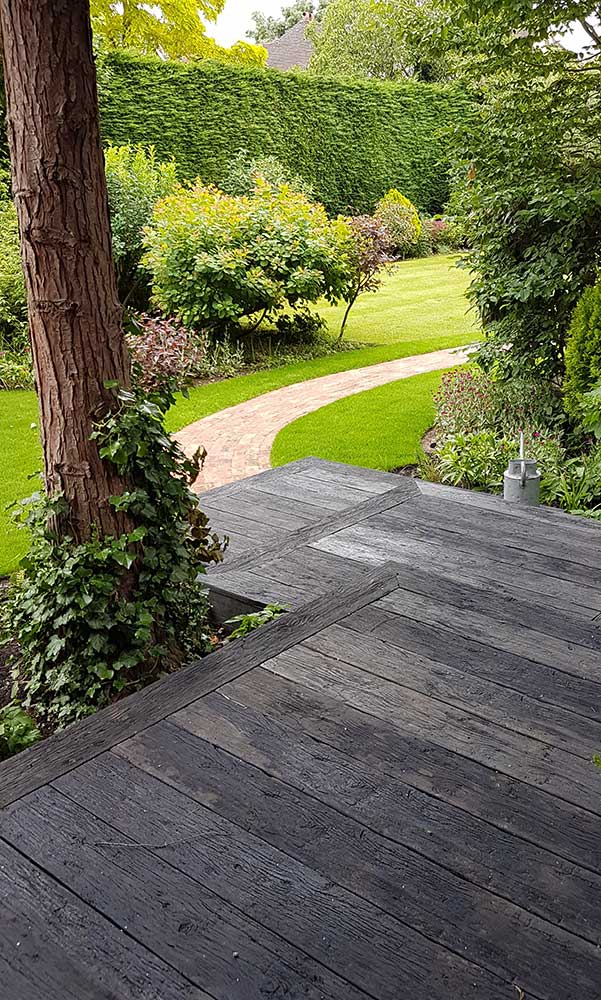 Embered Millboard composite decking descends by steps to path between trees.