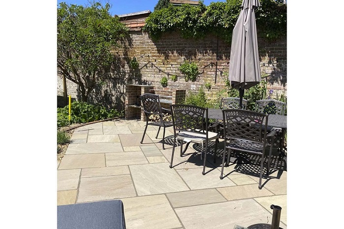 Walled garden with Raj Green Indian Sandstone paving with metal dining. Design set by Aye Gardening.