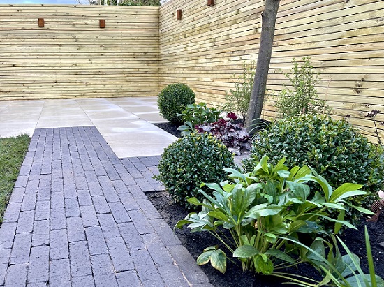 Amersham Clay Block Paving in interlinked paving design with Ash Beige porcelain. Planted border and slatted fencing.