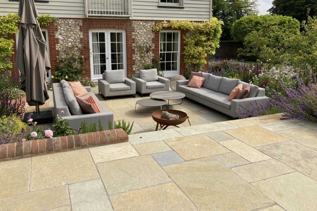 Antique Yellow tumbled limestone patio on 2 levels with outdoor furniture and firepit.