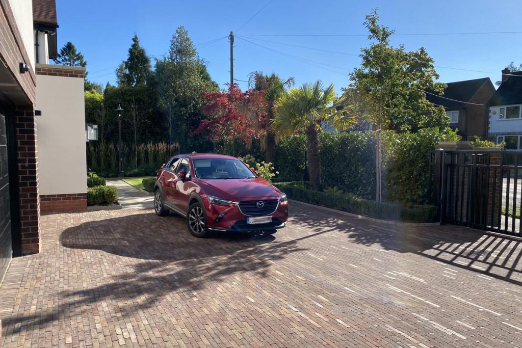 Bexhill clay paver driveway with red car and edged with hedging.