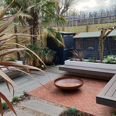 Delta Light Multi Clay Block Paving and Nuage Porcelain Plank Paving in back garden with water bowl and exotic planting.