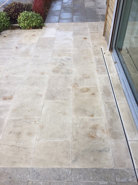 Leaf marks visible on Beige sawn sandstone patio after jet washing.