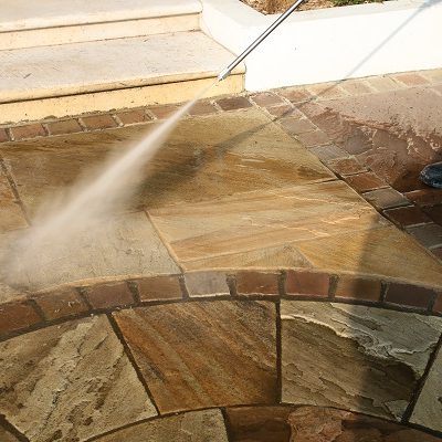Jet wash in action, held at correct angle and right distance from sandstone paving.