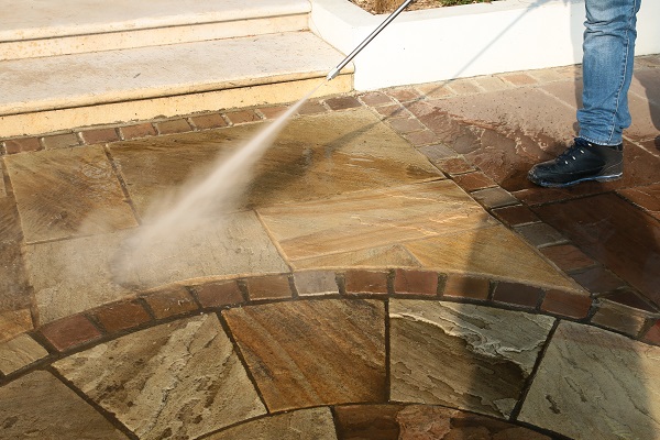 Jet wash in action, held at correct angle and right distance from sandstone paving.