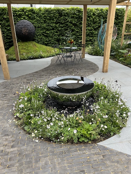 Lucca clay pavers and Trendy Black porcelain paving with round bed and central metal water feature
