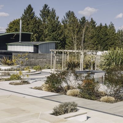 View across Kent showroom's external paving display of sandstone, with pergola and planting
