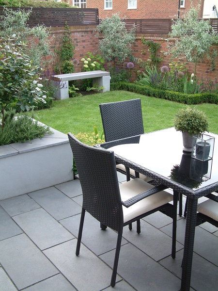 Outdoor dining set on Kota Blue limestone patio with lawn and white rendered raised bed.