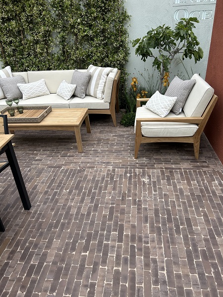 Verona clay pavers laid in 2 directions with cream-cushioned outdoor furniture against living wall.