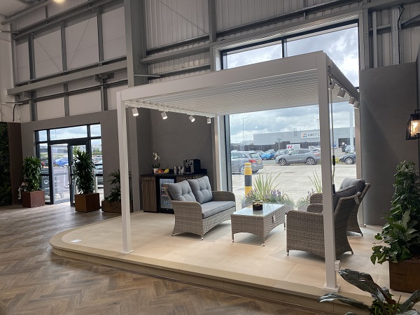 Proteus white aluminium pergola on dais next to large window in Bristol hard landscaping showroom.