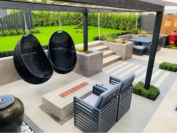 Cream and Steel Grey porcelain slabs and planks zone a wide 2 tone patio into areas for dining and relaxing. Steps up to lawn.