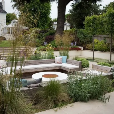 Large rectangular sunken seating in Golden Stone porcelain paved area with steps up to lawn at back of period house.