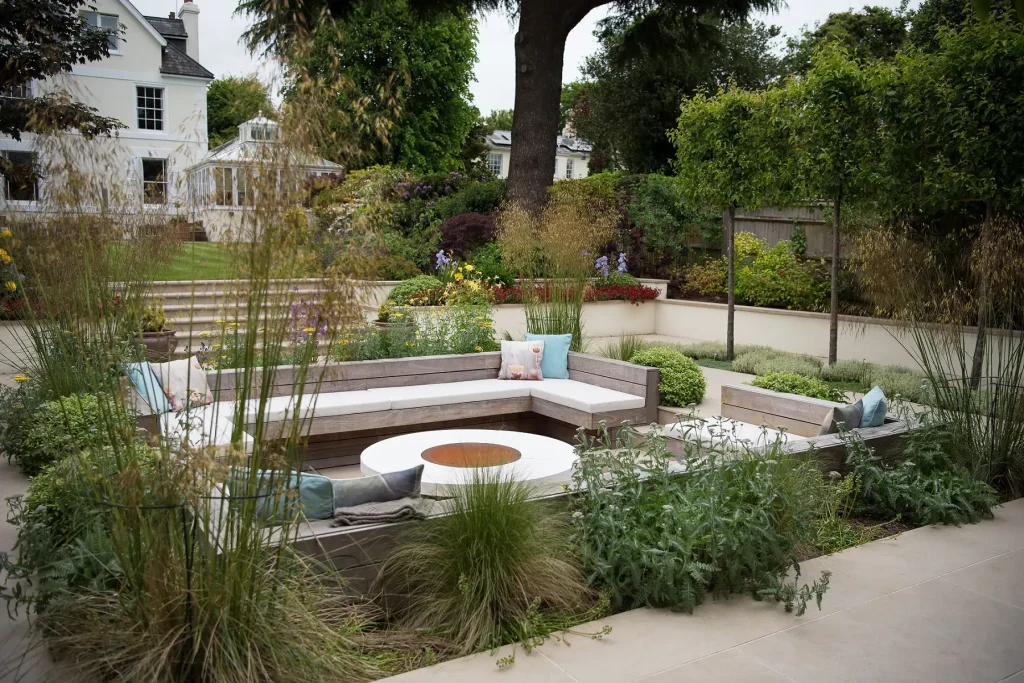 Large rectangular sunken seating in Golden Stone porcelain paved area with steps up to lawn at back of period house. 