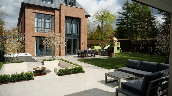 Largely paved back garden with sunken seating area and fire bowl, children's play equipment and furniture. Built by Radial