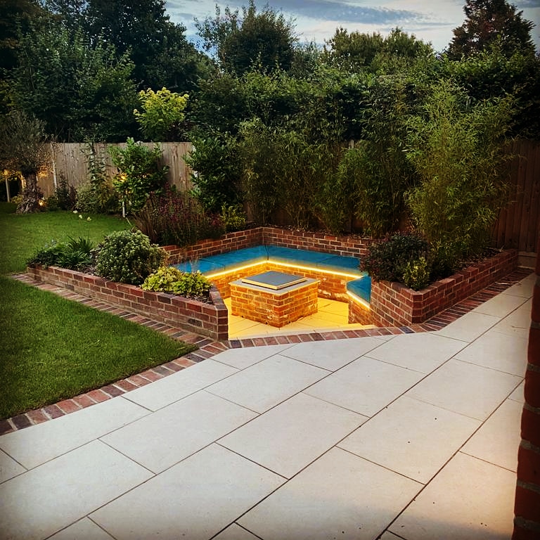 Square sunken seating area set at angle to patio, with firepit and underseat lighting. 