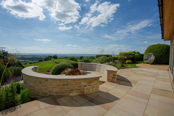 Round seating area in Buff sawn sandstone, with protective walls, looks out over countryside to horizon.