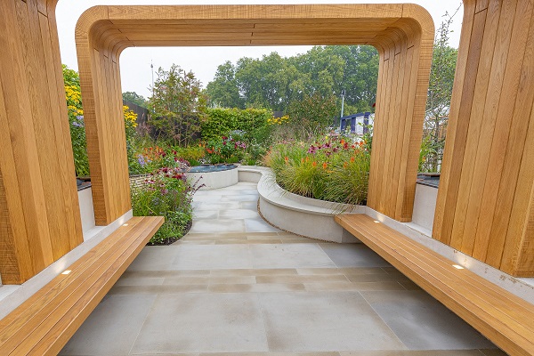 Wooden arch over Heathermoor Buff Yorkstone path narrowing between curved beds with coping.