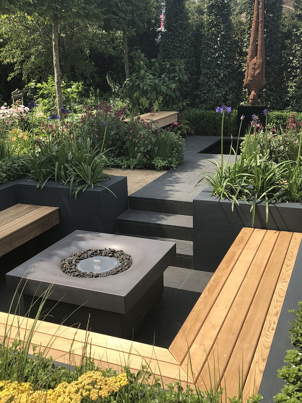 Natural stone patio idea of blue grey granite path between beds leads to steps down to bench seating around fire pit.