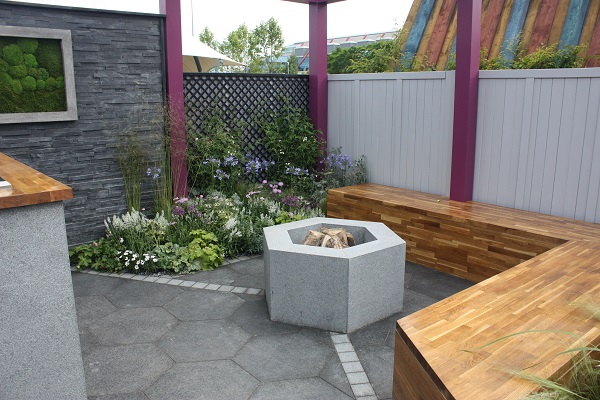 Fire pit stands on hexagonal Black Basalt paving by L-shaped bench in BBC Gardeners' World Live 2017 garden.