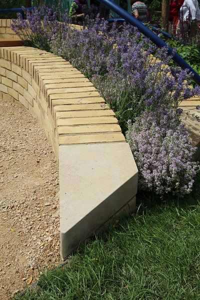 Buff Yorkstone quoin with angled end creates finish to curved brick wall next to Breedon gravel. 