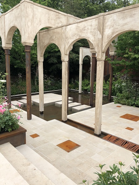 RHS Chelsea show garden with arched colonnade and pond with Jura beige limestone stepping stones