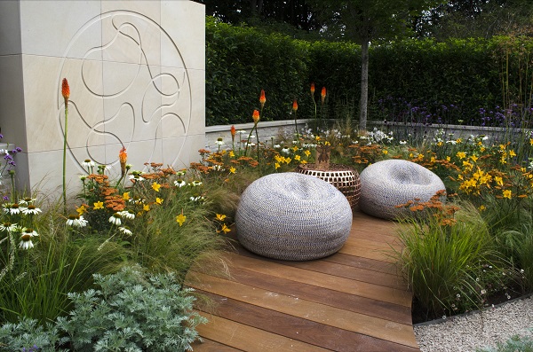 Harvest sawn sandstone block sculpture engraved with Xylella cell behind paved area in flowery garden at RHS Tatton Park 2019