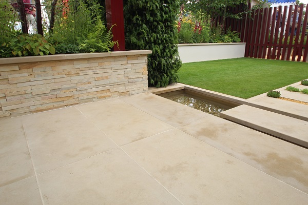 Paved area of Buff Yorkstone  with stepping stone in wide rill to lawn. 