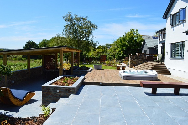 Terrace part paved with Kirkby blue porcelain outdoor tiles and decking. Steps descend past raised bed. 