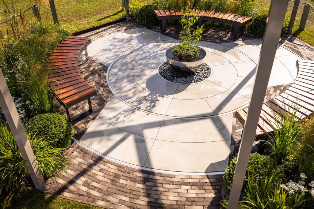 Radius cut Yard porcelain paving circle with 11 courses of Stone Grey clay pavers as edging.