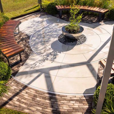 Radius cut Yard porcelain paving circle with 11 courses of Stone Grey clay pavers as edging.