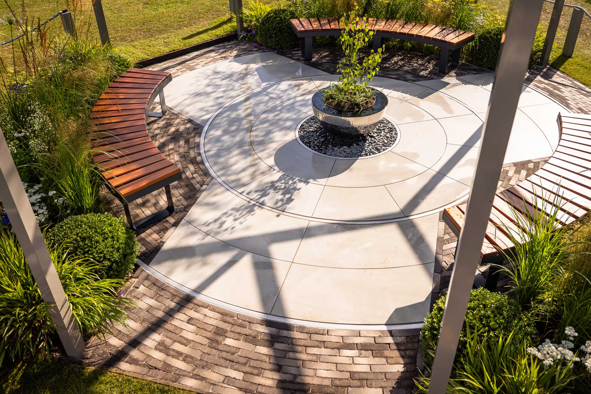 Radius cut Yard porcelain paving circle with 11 courses of Stone Grey clay pavers as edging.