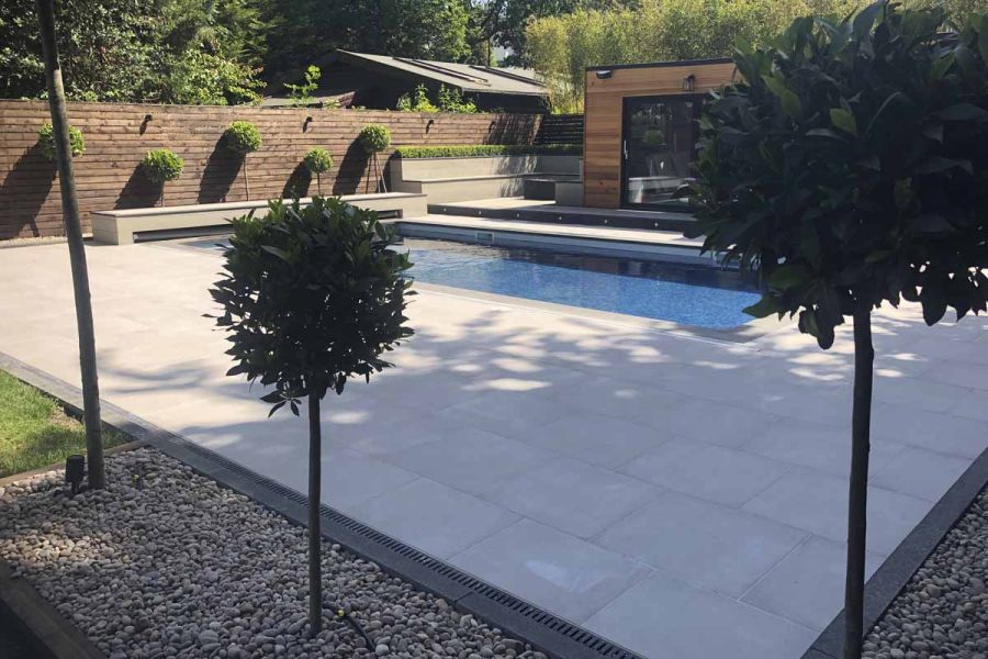 Patio of Cement porcelain outdoor tiles with dark grey edge tiles disguising channel drain.