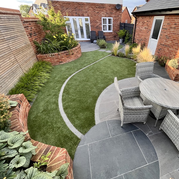 Charcoal porcelain circle overlaps with Platinum Grey circle to create patio in lawned garden. 