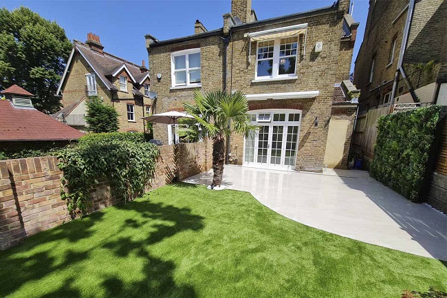 Period semi-detached house with curve-edged Kandla Grey porcelain patio and artificial lawn.
