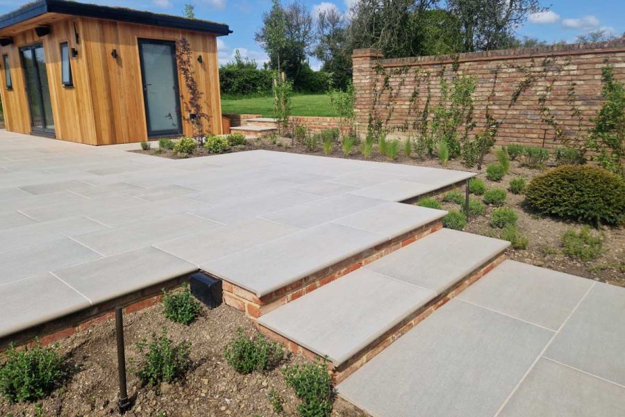 2 steps descend from rectangular urban grey porcelain patio with bullnose edging. 