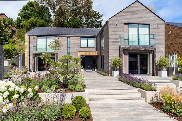 Modern house with large garden of planted beds and wide paths of Cinder wood-effect porcelain paving.