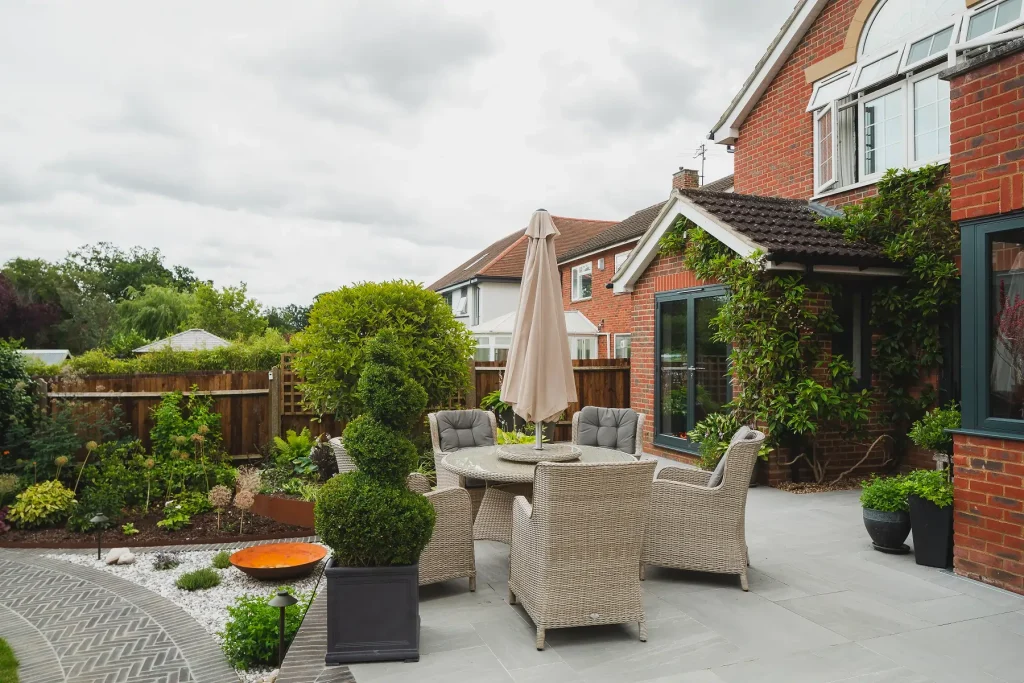 Kandla Grey porcelain patio edged with Moderna clay pavers that also form curved path around lawn.