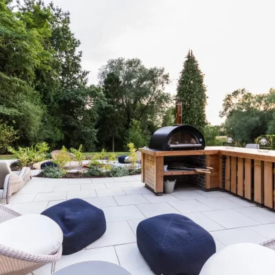 2 blue pouffes on large patio of Sandy White 600x600 porcelain slabs with dining bar and barbecue.