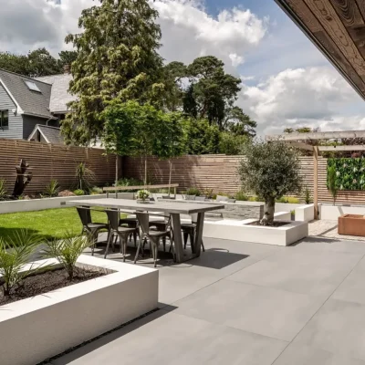 Large garden with rectangular raised beds and Sidewalk large format porcelain paving.