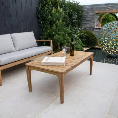 Sofa and table on Egyptian Beige Limestone paving with Millboard fence behind.