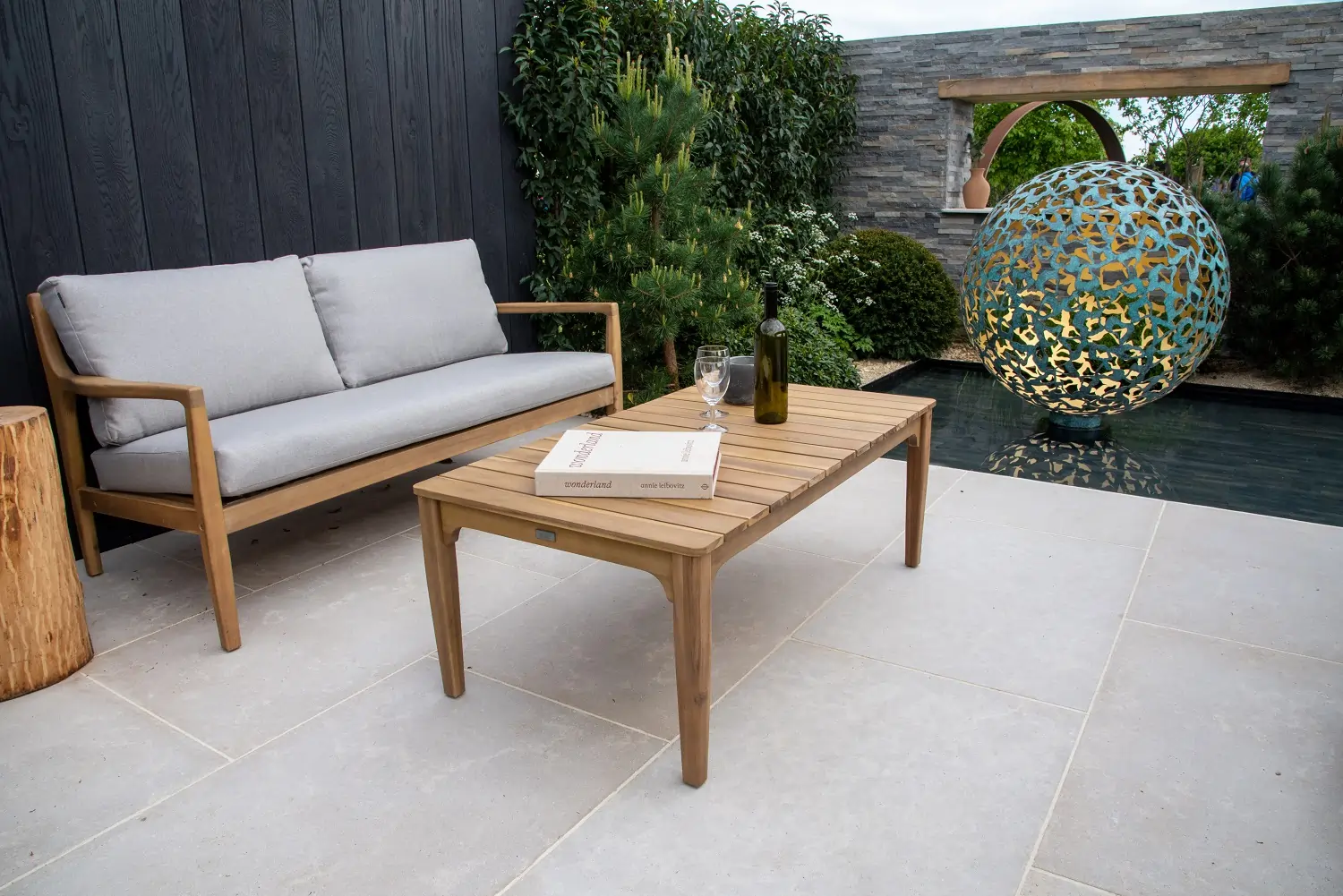 Sofa and table on Egyptian Beige Limestone paving with Millboard fence behind.