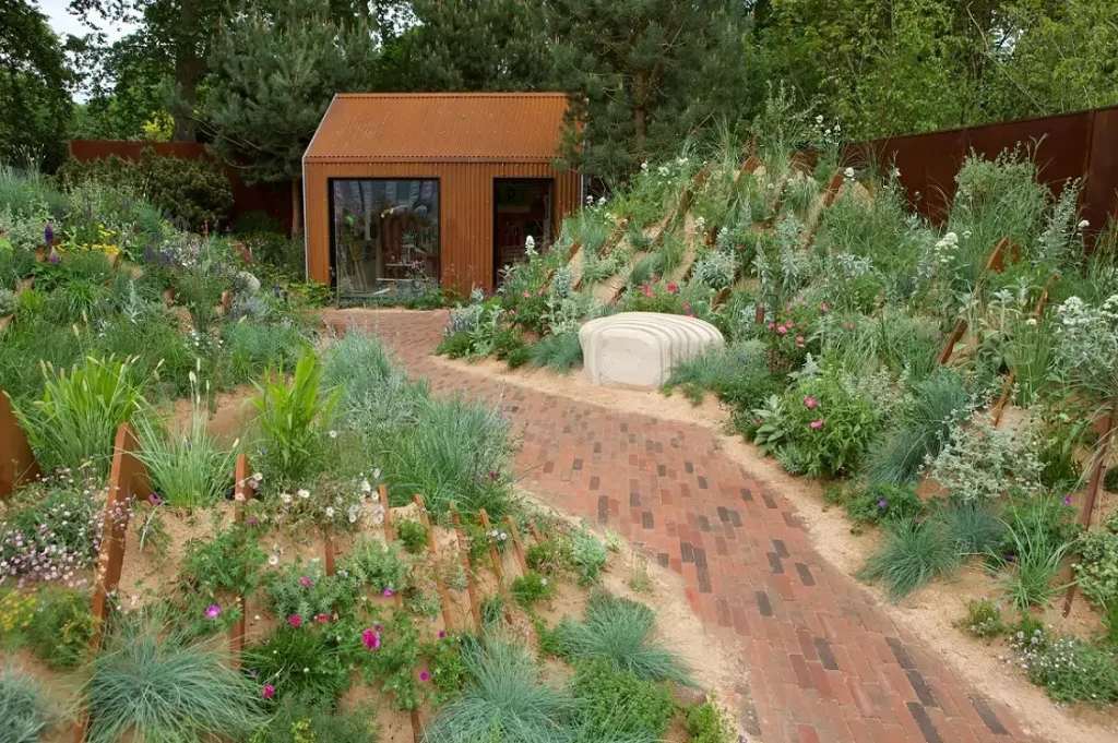Clay paver path runs getween planted sandy banks to a bothy, Hospitalfield Arts Garden, RHS Chelsea 2025