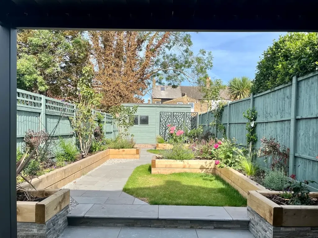 Graphite Grey limestone paving with step up to path down side of lawn in fenced garden