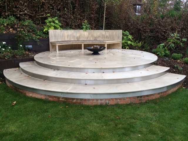 Raised patio with curved steps created with laser templating in Beige Sawn sandstone.