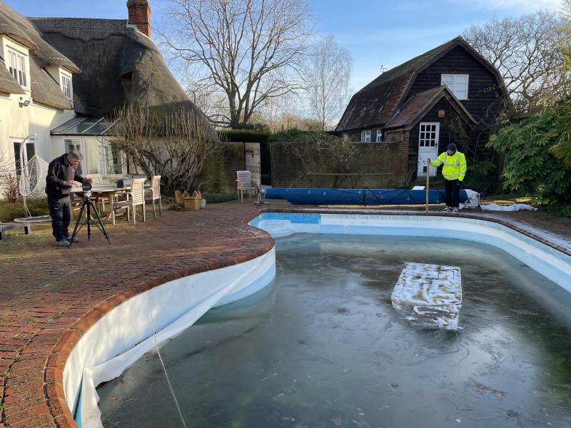 2 men take a digital laser template of the outline of a swimming pool.