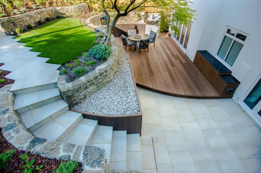 View down onto steps curving up from patio in Gea porcelain with curved edge to raised decking.