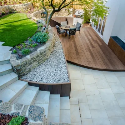 View down onto steps curving up from patio in Gea porcelain with curved edge to raised decking.