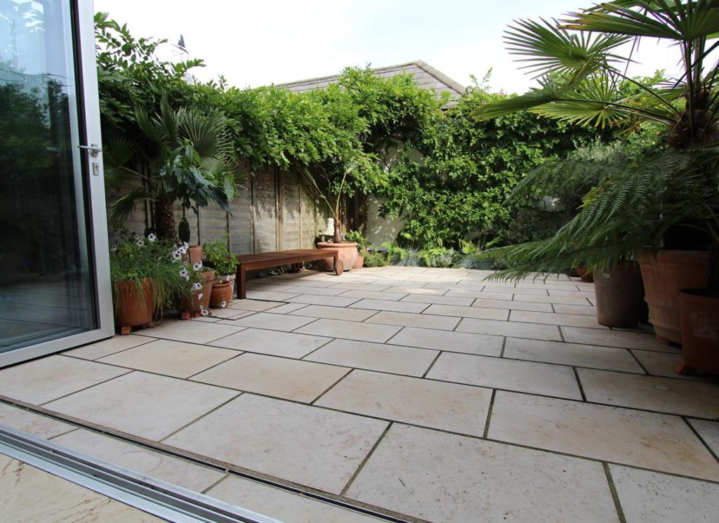 Fully paved small rectangular garden with bifold doors opening over slot drain.