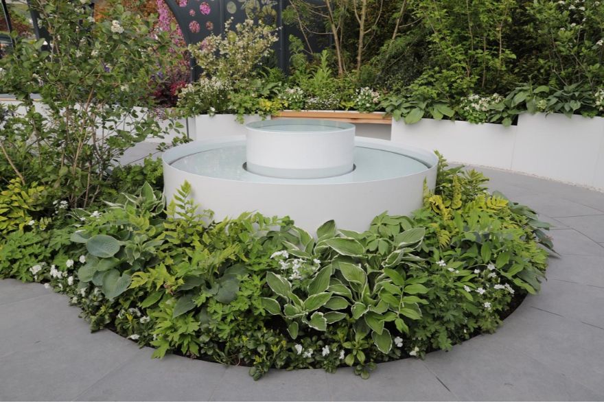 Round water feature with curved cut Anthracite porcelain paving surround.